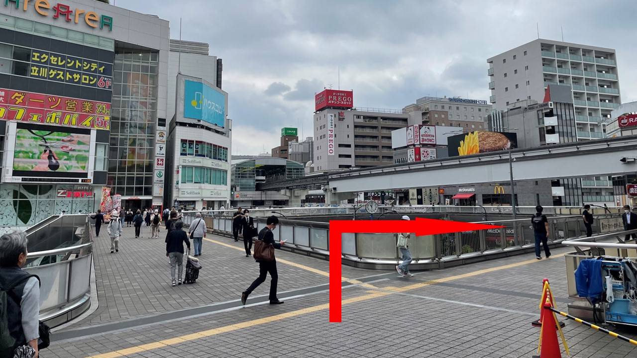 立川駅改札を出て南口へ進み、屋根が途切れた地点で右折し、正面に見える「アコム」の赤い看板に向かって歩道橋を直進してください。