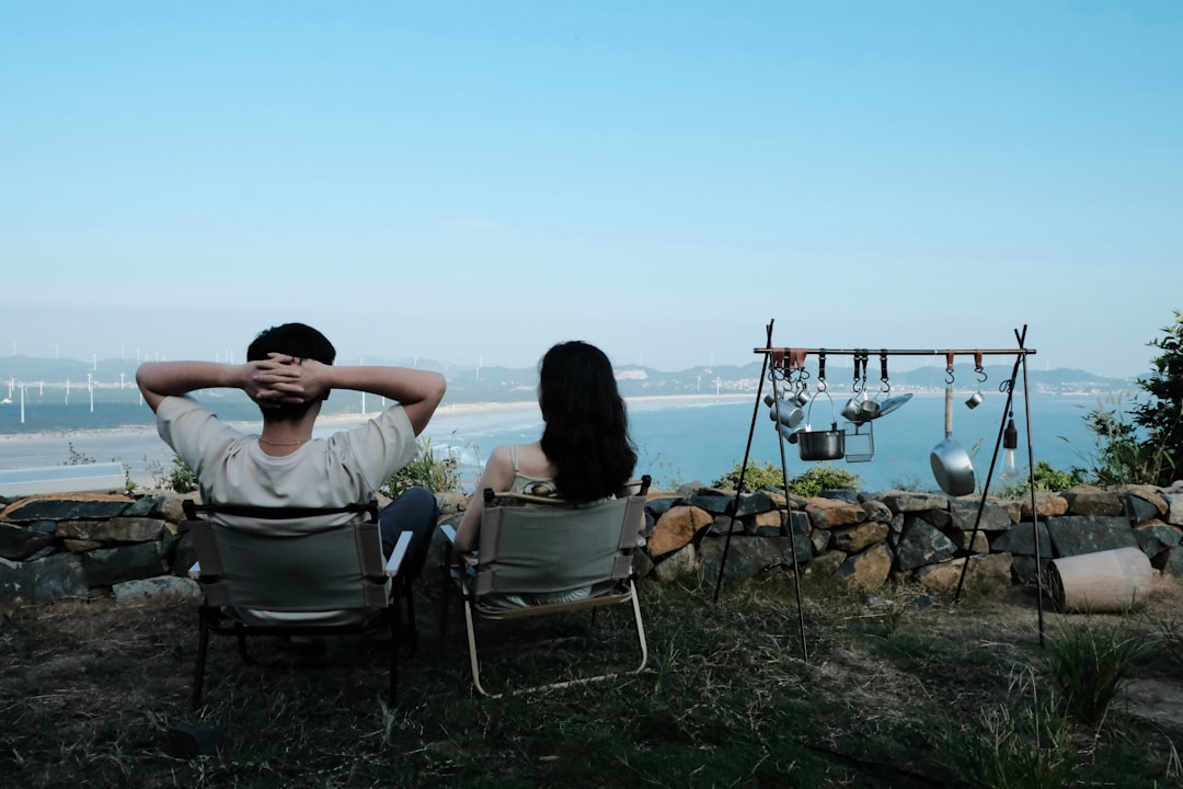 a man and woman sitting on a bench in front of a body of water